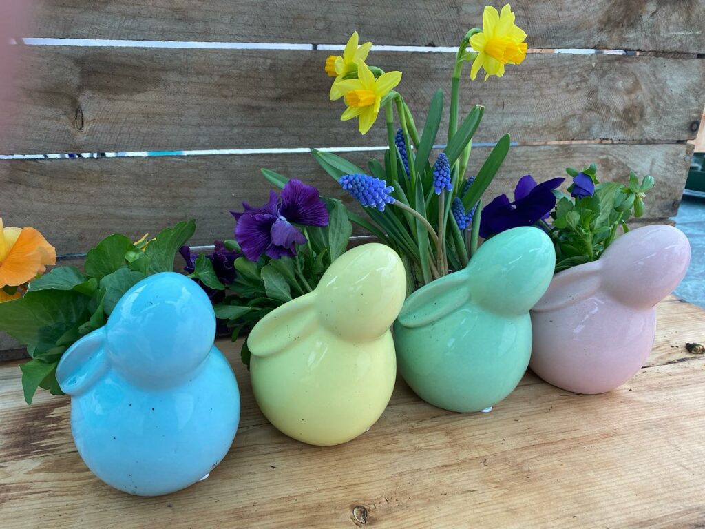 Colorful ceramic bird figurines among spring flowers.
